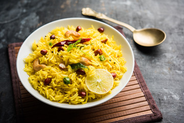 Lemon Rice is a South Indian turmeric rice or maharashtrian recipe called fodnicha bhat using leftover rice garnished with nuts curry leaves and lemon juice, selective focus