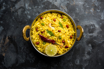 Lemon Rice is a South Indian turmeric rice or maharashtrian recipe called fodnicha bhat using leftover rice garnished with nuts curry leaves and lemon juice, selective focus