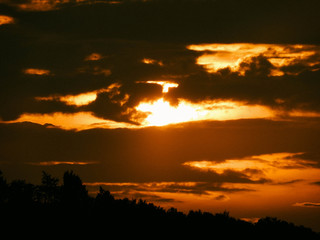 Red sunset with clouds and sunlight getting through the clouds