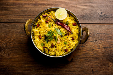 Lemon Rice is a South Indian turmeric rice or maharashtrian recipe called fodnicha bhat using leftover rice garnished with nuts curry leaves and lemon juice, selective focus