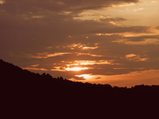 Red sunset with clouds and sunlight getting through the clouds