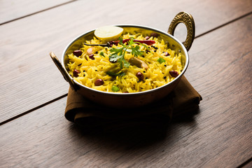 Lemon Rice is a South Indian turmeric rice or maharashtrian recipe called fodnicha bhat using leftover rice garnished with nuts curry leaves and lemon juice, selective focus