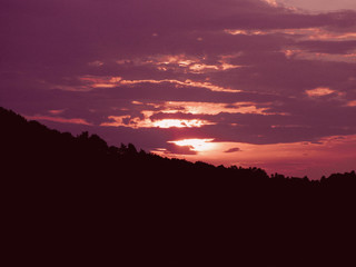 Red sunset with clouds and sunlight getting through the clouds