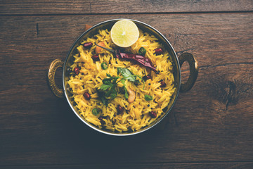 Lemon Rice is a South Indian turmeric rice or maharashtrian recipe called fodnicha bhat using leftover rice garnished with nuts curry leaves and lemon juice, selective focus