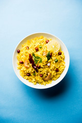 Lemon Rice is a South Indian turmeric rice or maharashtrian recipe called fodnicha bhat using leftover rice garnished with nuts curry leaves and lemon juice, selective focus