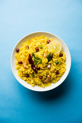 Lemon Rice is a South Indian turmeric rice or maharashtrian recipe called fodnicha bhat using leftover rice garnished with nuts curry leaves and lemon juice, selective focus