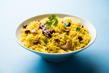 Lemon Rice is a South Indian turmeric rice or maharashtrian recipe called fodnicha bhat using leftover rice garnished with nuts curry leaves and lemon juice, selective focus