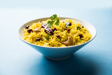 Lemon Rice is a South Indian turmeric rice or maharashtrian recipe called fodnicha bhat using leftover rice garnished with nuts curry leaves and lemon juice, selective focus