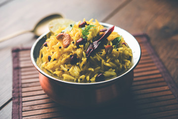 Lemon Rice is a South Indian turmeric rice or maharashtrian recipe called fodnicha bhat using leftover rice garnished with nuts curry leaves and lemon juice, selective focus