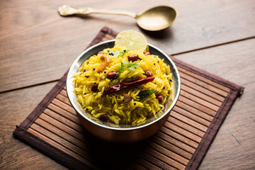 Lemon Rice is a South Indian turmeric rice or maharashtrian recipe called fodnicha bhat using leftover rice garnished with nuts curry leaves and lemon juice, selective focus