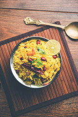 Lemon Rice is a South Indian turmeric rice or maharashtrian recipe called fodnicha bhat using leftover rice garnished with nuts curry leaves and lemon juice, selective focus