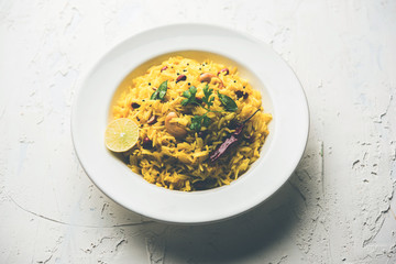 Lemon Rice is a South Indian turmeric rice or maharashtrian recipe called fodnicha bhat using leftover rice garnished with nuts curry leaves and lemon juice, selective focus