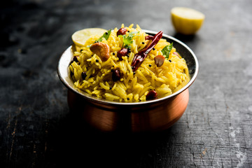 Lemon Rice is a South Indian turmeric rice or maharashtrian recipe called fodnicha bhat using leftover rice garnished with nuts curry leaves and lemon juice, selective focus