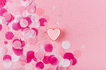 heart with confetti on pink background. Top view