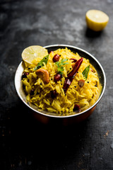 Lemon Rice is a South Indian turmeric rice or maharashtrian recipe called fodnicha bhat using leftover rice garnished with nuts curry leaves and lemon juice, selective focus