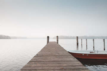 rotes Ruderboot an einem Holzsteg im Spreewald. Aufgenommen an einem nebeligen Tag im Spätherbst.