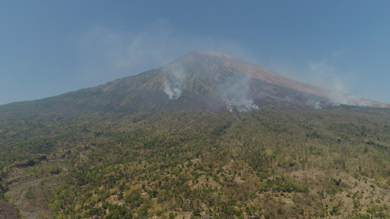 slopes volcano with forest fire, farmland at foot of the volcano Agung. tropical landscape aerial view mountains are covered with forest. Bali, Indonesia.