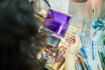 High angle close up of female hands shaping glass over gas torch while making beads for beautiful handmade jewelry in glassworking studio, copy space