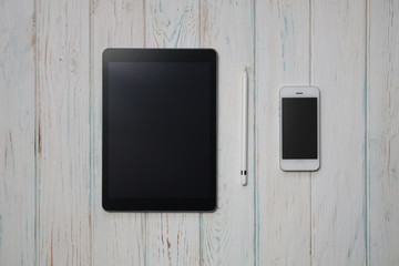 mockup tablet and smartphone on wood desk. Black display. Mobile phone, pad and notepad with pen, workplace, top view