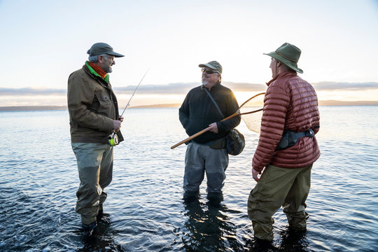 Two fly fisherman talk wtih their guide about new tecnhiques while fly fishing for searun coastal cutthroat trout at a beach on the north west coastline of the USA. 