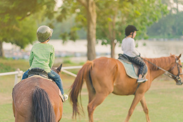 Kids learn to ride a horse near the river before sunset.