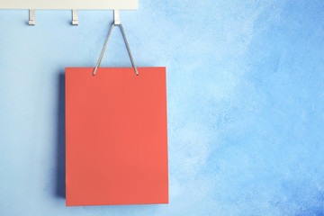 Rack with paper shopping bag on color wall. Mockup for design