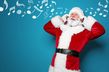 Santa Claus listening to Christmas music on color background