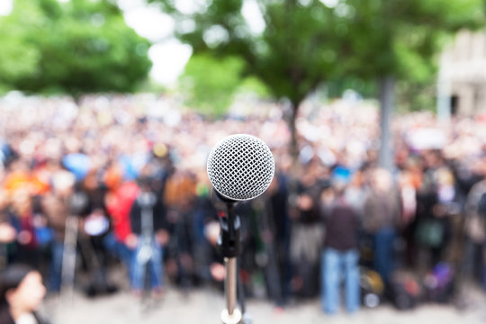 Microphone in focus against blurred protest or public demonstration