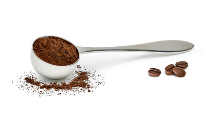 Grinded coffee powder in measuring scoop with beans isolated on white background