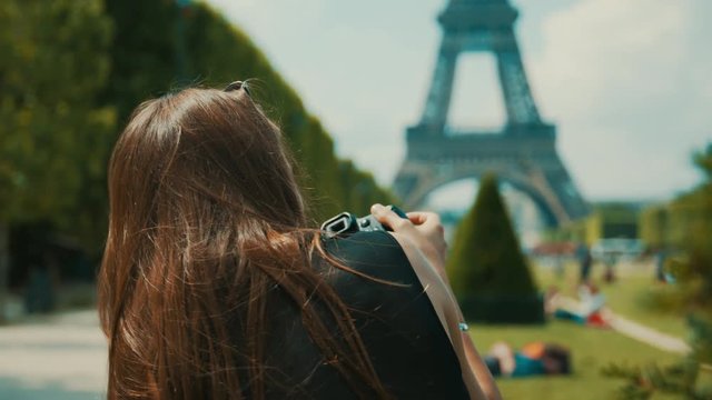 Pretty young female photographer takes a picture of the Eiffel Tower then looks at the photo on her digital camera