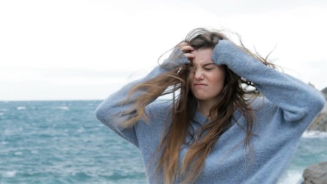 Angry teen walking with tousled hair in a windy day on the beach