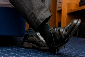 Tired business man kicking off shoes in hotel room