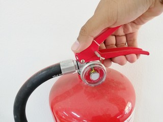 Man hand is holding a red fire extinguisher.