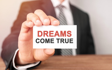 Businessman holding a card with text Dreams Come True