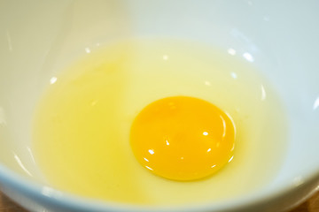raw whole egg on white bowl ready to cook