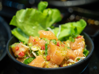 salmon mix spicy salad on black bowl in japanase restaurant