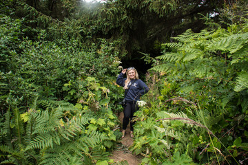 An adult female hiker stands in lush vegetation of Patricks Point State Park in Northern California...