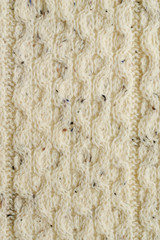 Knitted white fabric texture from wool with a relief pattern. Warm winter clothes or blanket. Handmade texture. Background of knitted sweaters decoration