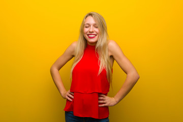 Young girl with red dress over yellow wall happy and smiling