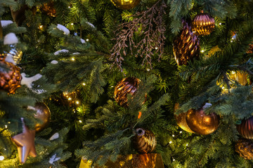 Christmas tree closeup. Golden balls and illuminated garland with flashlights.
