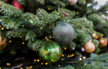 Christmas tree closeup. Green and golden balls and illuminated garland with flashlights.