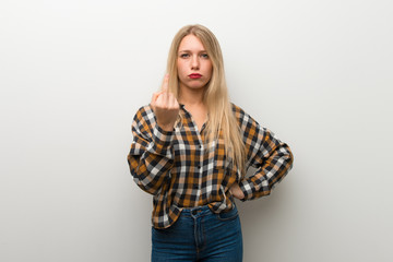 Blonde young girl over white wall making horn gesture