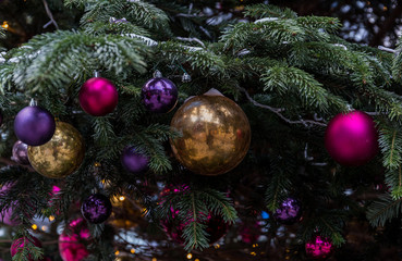 Christmas tree closeup. Red and golden balls and illuminated garland with flashlights.