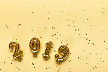 Fototapeta na wymiar top view of golden 2019 candles and festive confetti on beige background
