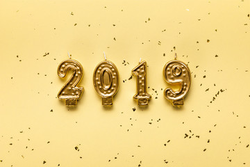 Fototapeta na wymiar golden 2019 candles and festive confetti on beige background