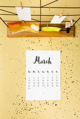 top view of march calendar with golden confetti and cards with clothespins on beige