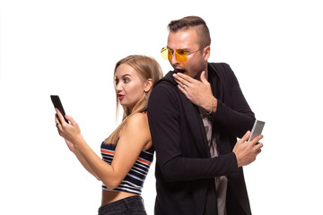 Man and woman stand with their backs to each other with telephones in their hands on white background