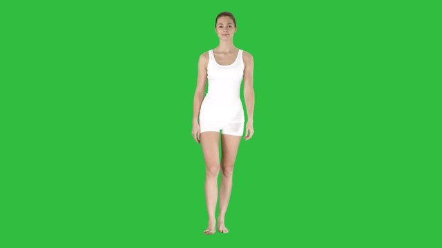 Young blonde woman walking and pointing to side showing on something on a Green Screen, Chroma Key.
