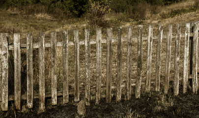 Rural view of a poor Ukrainian village - an old wooden fence in the countryside. Traditional old wooden fence as a rural landscape
