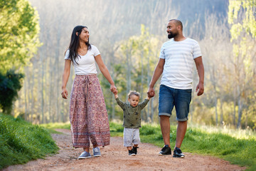 Happy mixed race family smiling walking along path